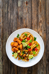 Asian food - chicken nuggets, noodles and fried shimeji mushrooms on wooden table
