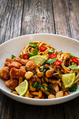 Asian food - chicken nuggets, noodles and fried shimeji mushrooms on wooden table
