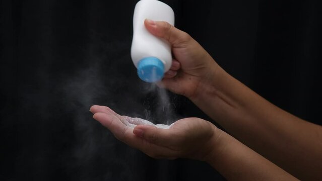 Female hand with talcum powder isolated on black background.