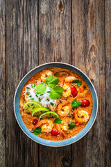 Tom Yum soup - Thai soup with prawns and rice noodles on wooden table

