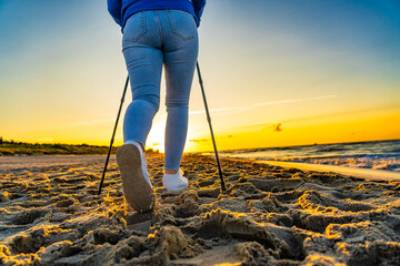 Nordic walking - woman exercising on beach at sunset
