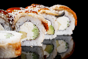sushi roll with avocado cucumber cream cheese eel unagi on a black mirror background
