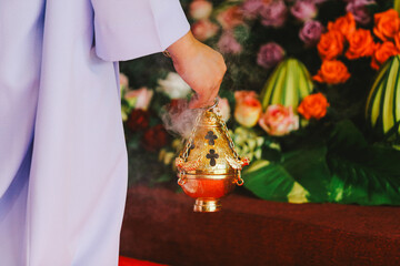 Close-up image of a Catholic man praying in the church.religious golden censer against the...