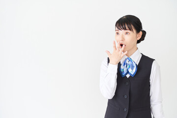 驚くポーズをするベストにリボンタイの制服を着た、受付業務、事務業務の女性