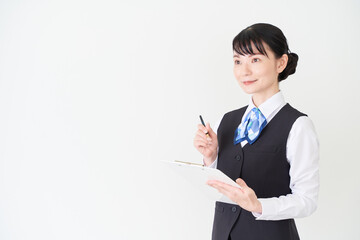 書類を書くベストにリボンタイの制服を着た、受付業務、事務業務の女性