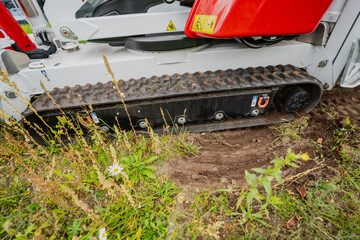 Construction compact loader rubber tracks on grass and ground moving earth
