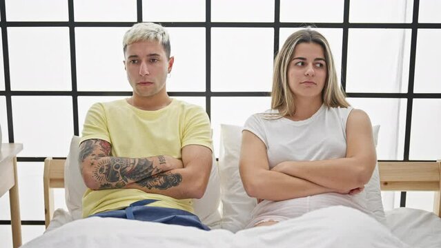 Beautiful couple couple sitting on bed arguing at bedroom