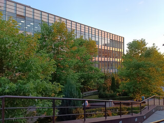 Modern office building surrounded by green trees. Eco architecture. Multiple story building with glass facade