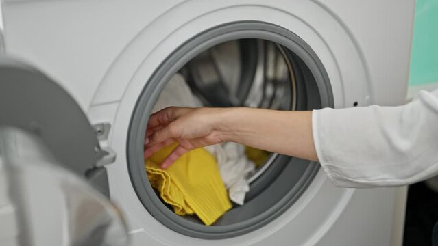 Young redhead woman putting detergent bag on washing machine at laundry room