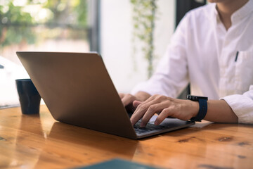 Fototapeta premium Young businessman in white shirt typing on laptop, searching information or working online