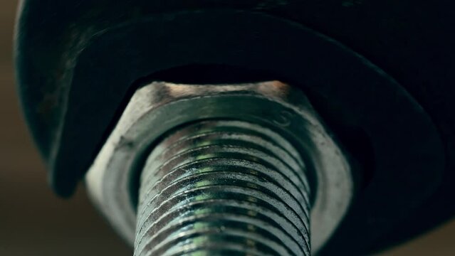 Tightening a big metallic nut with a large black wrench. View from below