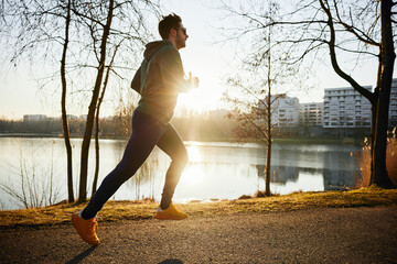 Male runner in park during autumn or winter sunset