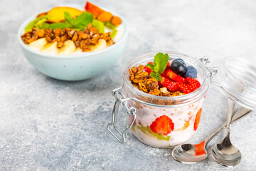 Bowl of granola with yogurt and fresh berries on a texture table. Yogurt berries, acai bowl, spirulina bowl. Healthy food, balanced breakfast. Strawberries, blueberries, kiwi, peach, almonds and chia.
