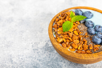 Bowl of granola with yogurt and fresh berries on a texture table. Yogurt berries, acai bowl, spirulina bowl. Healthy food, balanced breakfast. Strawberries, blueberries, kiwi, peach, almonds and chia.
