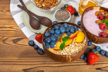 Bowl of granola with yogurt and fresh berries on a texture table. Yogurt berries, acai bowl, spirulina bowl. Healthy food, balanced breakfast. Strawberries, blueberries, kiwi, peach, almonds and chia.