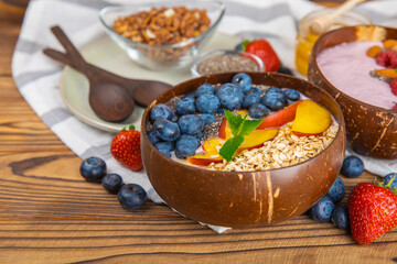 Bowl of granola with yogurt and fresh berries on a texture table. Yogurt berries, acai bowl, spirulina bowl. Healthy food, balanced breakfast. Strawberries, blueberries, kiwi, peach, almonds and chia.