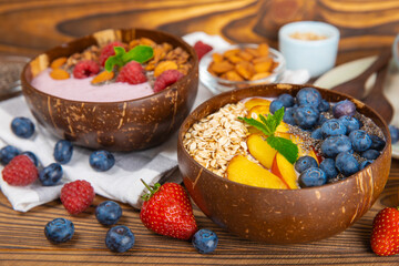 Bowl of granola with yogurt and fresh berries on a texture table. Yogurt berries, acai bowl, spirulina bowl. Healthy food, balanced breakfast. Strawberries, blueberries, kiwi, peach, almonds and chia.
