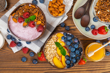 Bowl of granola with yogurt and fresh berries on a texture table. Yogurt berries, acai bowl, spirulina bowl. Healthy food, balanced breakfast. Strawberries, blueberries, kiwi, peach, almonds and chia.