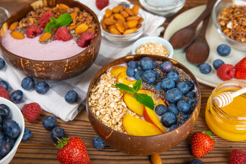 Bowl of granola with yogurt and fresh berries on a texture table. Yogurt berries, acai bowl, spirulina bowl. Healthy food, balanced breakfast. Strawberries, blueberries, kiwi, peach, almonds and chia.