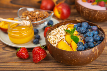 Bowl of granola with yogurt and fresh berries on a texture table. Yogurt berries, acai bowl, spirulina bowl. Healthy food, balanced breakfast. Strawberries, blueberries, kiwi, peach, almonds and chia.