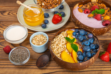 Bowl of granola with yogurt and fresh berries on a texture table. Yogurt berries, acai bowl, spirulina bowl. Healthy food, balanced breakfast. Strawberries, blueberries, kiwi, peach, almonds and chia.