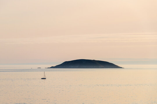 A lonely boat sails by Onza Island in the Ria de Pontevedra in Galicia during sunset.