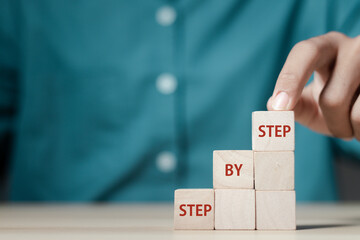 Businessman arranges wooden blocks with the text step by step. success or business progress.