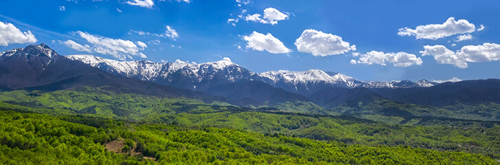 Fototapeta na wymiar panoramic view from a drone of the mountain with snow peaks and green hills.