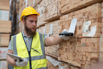 Male worker using scanner machine scanning barcode on label for checking plank wood stock inventory...