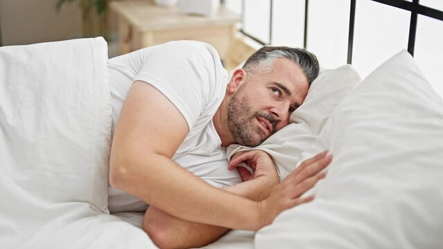 Grey-haired man covering ears for noise at bedroom