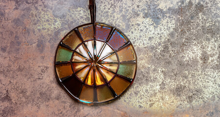 immagine con ciondolo, pendaglio in metallo e vetro colorato su superficie in materiale rustico