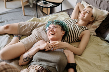 Obraz na płótnie Canvas Happy lesbian girls relaxing on bed in bedroom and enjoying each other