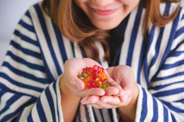 Closeup image of a young woman holding jelly gummy bears