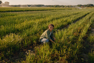 Naklejka na ściany i meble Smiling female farmer on field during harvesting. Agricultural occupation concept