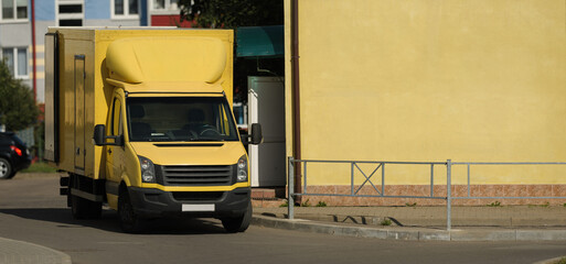 
a yellow truck stands on the street next to a yellow building