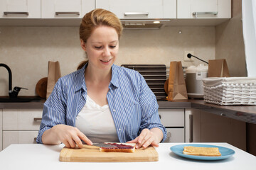 A mother preparing a peanut butter sandwich for her child's school lunch, spreading the creamy...