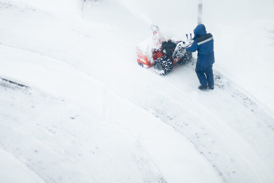 snowblower removes snow, a man cleans the yard outside