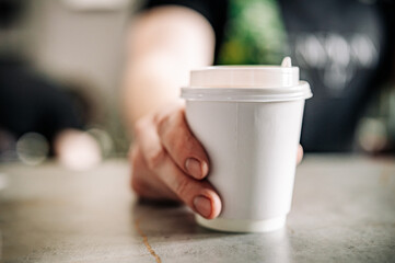 Barista hold a takeaway coffee in a paper cup