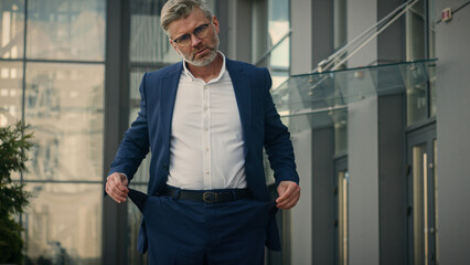 Caucasian mature sad senior business man show turn empty pants pockets bankrupt no money poverty...