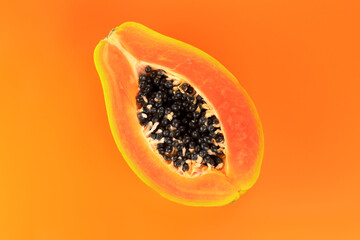 Papaya fruit on orange, yellow background. Half of fresh organic Papaya exotic fruit close up. Top view