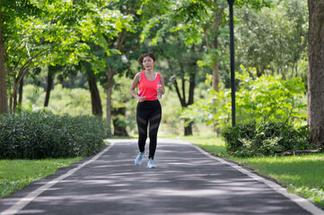 Fototapeta premium Asian female runner running on the street outdoors in the park