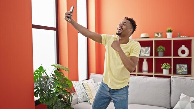 African american man having video call dancing at home