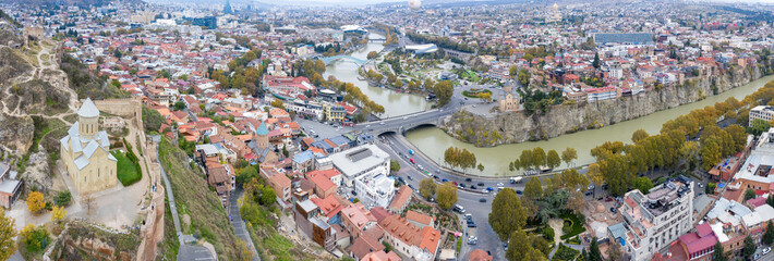 Panoramic drone view of Old Town, Narikala Fortress and Kura river on cloudy autumn day. Tbilisi, Georgia.