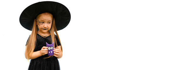 Banner with portrait of a little girl in a witch costume with a spider web pattern on his face and purple monster in his hands on the white background. Copy space.