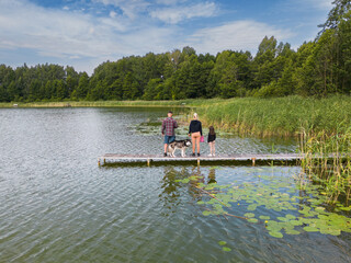 A young family with a husky dog ​​relaxes on the lake on a summer day.