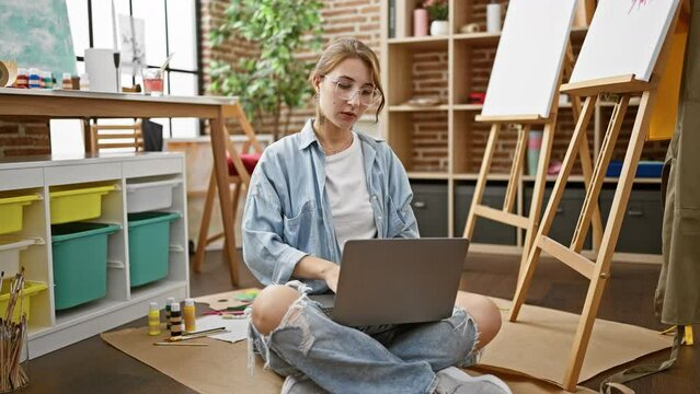 Young woman artist closing laptop stretching arms at art studio
