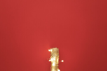 Champagne bottle with garlands on color background