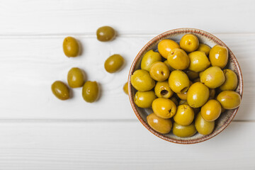 Greens olives on a white wooden background. Various types of olives in bowls and olive oil with fresh olive leaves. Copy space. Place for text. Mediterranean food. Vegan.