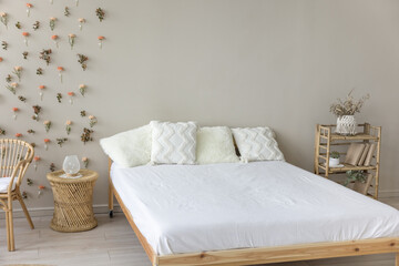 Wooden double bed with comfortable orthopedic mattress, white sheet, cushions in eco interior design. Stylish modern empty bedroom with no people, natural decoration, bamboo furniture - obrazy, fototapety, plakaty