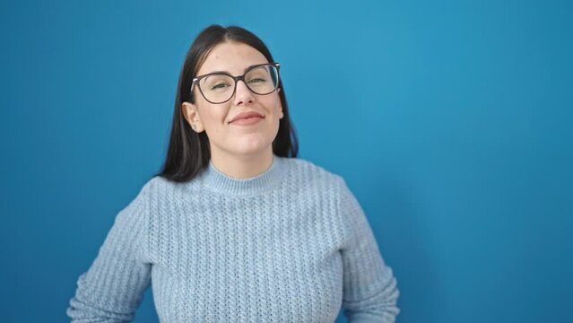Young hispanic woman smiling confident approving nodding with head over isolated blue background